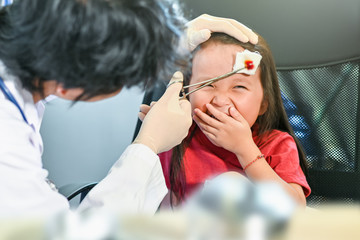 Doctor dressing wound on head little girl focus on little girl face wry face because hurt