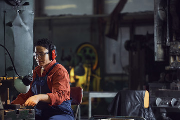 Portrait of modern African-American woman operating industrial machine units at metalworking plant, copy space