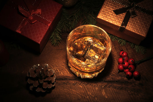 Glass with cognac or whiskey, Christmas balls and candles. New Year's tree, balls and glass with alcohol. Happy holidays decoration.