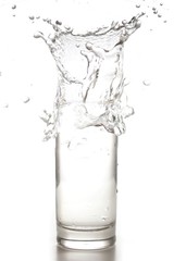 Fototapeta na wymiar water or drink splash out of a glass isolated on white background