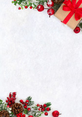 Christmas decoration, banner. Gift box with red ribbon, bow, twigs christmas tree, red berries and apples on snow with space for text. Top view, flat lay