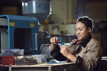 Portrait of smiling African-American woman working at production line at factory, copy space