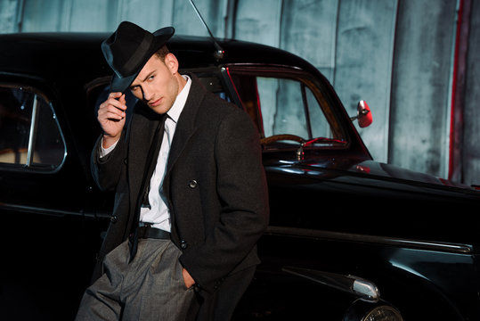 Stylish Man Touching Hat While Standing With Hand In Pocket Near Retro Car