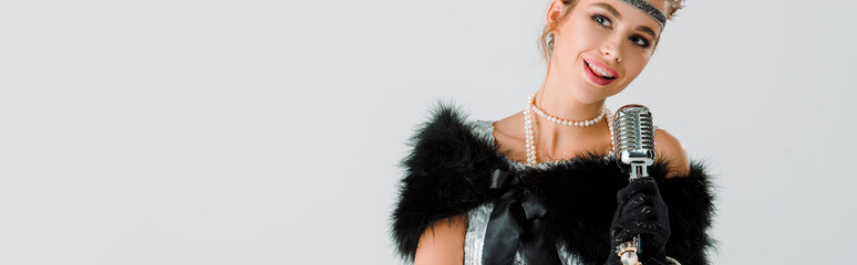 panoramic shot of happy woman near retro microphone isolated on white