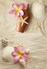 suntan lotion bottle and seashells on sand beach