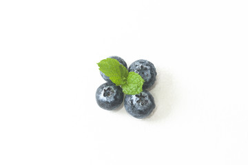 Blueberries and a mint leaf on a white background