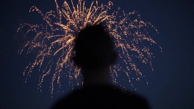 Blurred closeup silhouette of a man enjoying fireworks at night