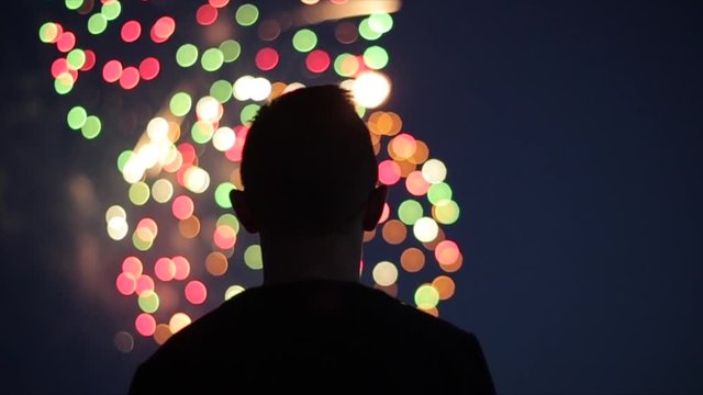 Blurred closeup silhouette of a man enjoying fireworks at night