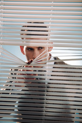 man touching window binds and looking away