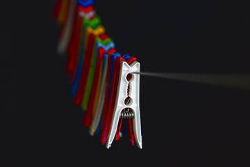Colorful pegs lined up on rope on a black backdrop.