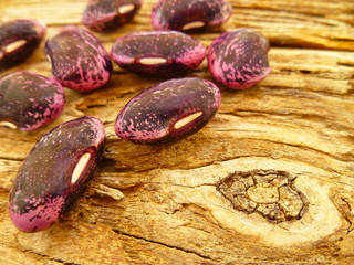 Pink and black large ripe raw beans on old  wooden background. Variety of protein rich colorful fresh raw beans. Selective soft focus, close up.