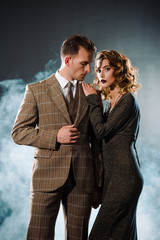 attractive woman standing with handsome gangster on black with smoke
