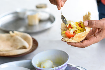 Arabian Male Having Breakfast At Home. Simple and tasty food. Fresh Pita stuffed with egg and tomato, spice and olive oil.