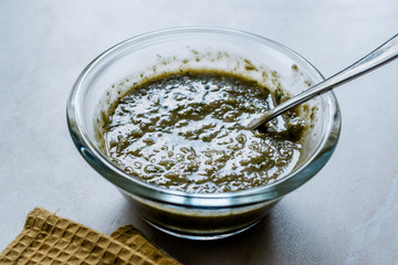 Homemade Green Herbal Salad Sauce with Plant Roots in Glass Bowl with Spoon.