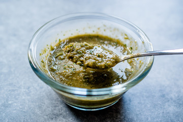 Homemade Green Herbal Salad Sauce with Plant Roots in Glass Bowl with Spoon.