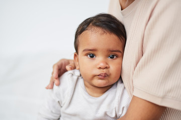 Portrait of African baby boy looking at camera while sitting on his mother's knees