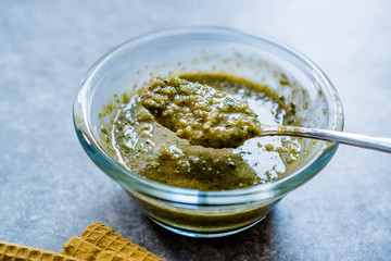 Homemade Green Herbal Salad Sauce with Plant Roots in Glass Bowl with Spoon.
