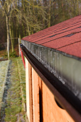 Modern roof shingles tiles. Soft asphalt roof cover and roofing construction for a small house in the garden. Easy roofing repair. Czech republic, Europe.