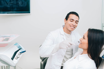 Afro american dentist exam teeth to a female patient at dental clinic.