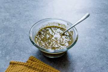 Homemade Green Herbal Salad Sauce with Plant Roots in Glass Bowl with Spoon.