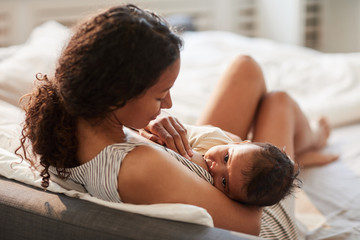 High angle portrait of young African-American mother breastfeeding cute baby boy with child looking at camera, copy space - obrazy, fototapety, plakaty