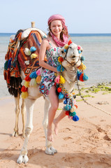 beautiful young girl riding a camel on a seascape background