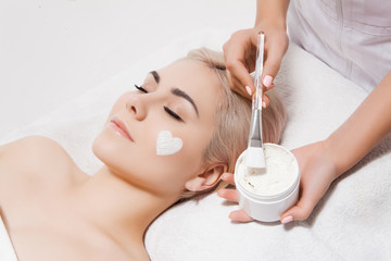 Obraz na płótnie Canvas Face peeling mask, spa beauty treatment, skincare. Woman getting facial care by beautician in spa salon. Model lying on couch with closed eyes in cosmetological clinic. Healthcare clinic cosmetology