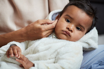 Close-up of cute baby boy lying on his mother's hands while she stroking his head and cradling him