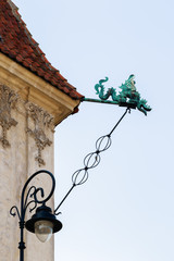 Fototapeta na wymiar A metal Gargoyle representing dragon with a spout, designed to carry water from the roof in Old Town Market Square, Warsaw, Poland, in spring