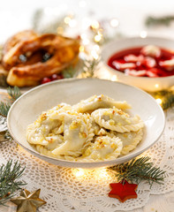 Christmas dumplings stuffed with forest mushrooms and cabbage on a white plate on a white holiday table. Traditional Christmas eve dish in Poland