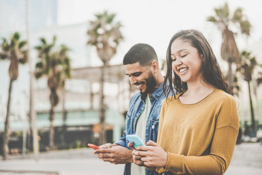 Latin couple shopping online using smartphone app - Young people having fun with new e-commerce technology trend - Social network, tech and millennial concept - Focus on girl face