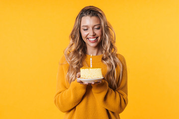 Image of cheerful woman smiling and holding birthday cake with candle