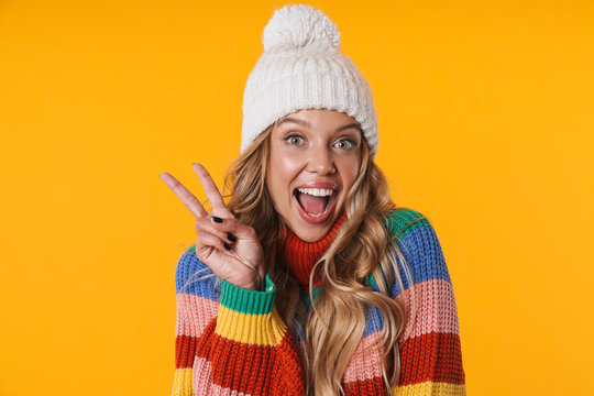 Image of happy woman in winter hat laughing and showing peace fingers