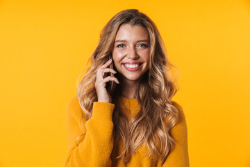 Image of joyful blonde woman smiling and talking on cellphone