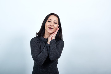 Sleepy caucasian young woman in fashion black sweater over isolated white background holding hand on cheek, doing sleep gesture, smiling, Lifestyle concept