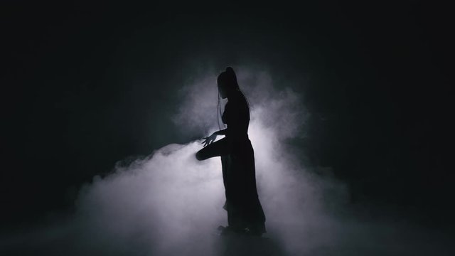 Silhouette dancer woman performing dance figures in fog. 4K Slow motion footage.