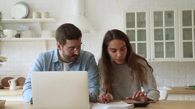 Serious young couple paying bills online on website app