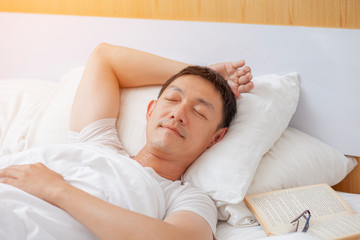 Fototapeta na wymiar Man Sleeping in Comfortable White Bed at Home. Rest Roncepts. Resting at Home. White Bed. Healthy Lifestyle Concept. Elder Person in Bed. Sleeping Man. Napping Old Man. Dreams in Bed.