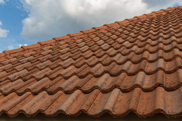 roof top on sky background. Close up of brown clay roof tiles. Red old dirty roof. Old roof tiles. Construction equipment build a house.
