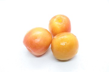 Orange wet tasty plums located on a white background