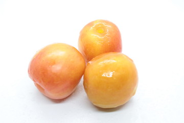 Orange wet tasty plums located on a white background