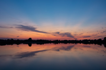 Colorful clouds after sunset, mirror reflection in lake
