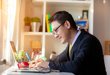 Casual businessman working in office, sitting at desk, typing on keyboard, looking at computer screen.