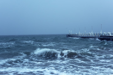 Winter sea landscape. Long exposure. The icy sea and the pier in ice, frozen icicles.