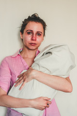 Crying young mother holds her baby on white background. Concept of postpartum depression