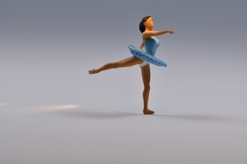 Fototapeta na wymiar Tiny ballerina dancer in blue dress standing on one leg