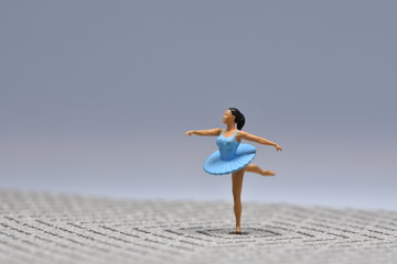 Fototapeta premium Tiny ballerina dancer in blue dress standing on one leg