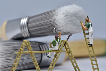 tiny painters are painting. Standing on a ladder, walking around brushes