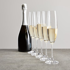 selective focus of champagne glasses with sparkling wine near bottle isolated on grey © LIGHTFIELD STUDIOS