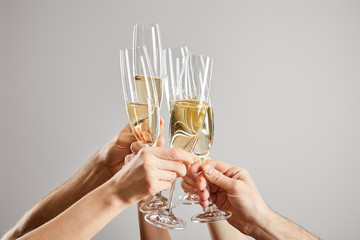 cropped view of men and women toasting champagne glasses with fresh sparkling wine isolated on grey